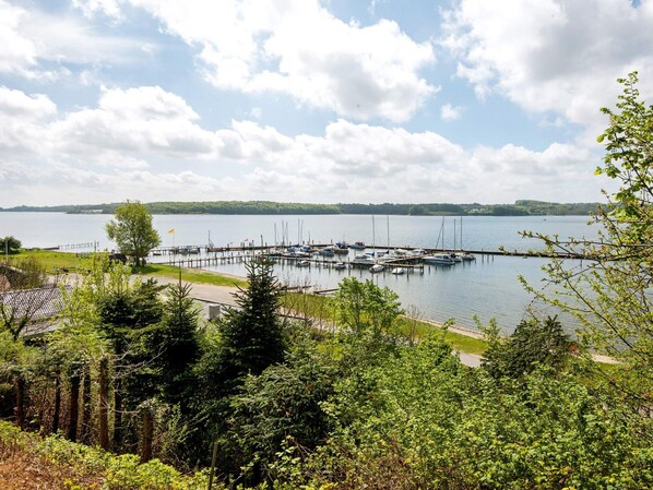 A marina with boats docked, surrounded by dense greenery and a clear sky.