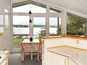 A kitchen with a view of a lake, a dining table with chairs, and a hanging light fixture.