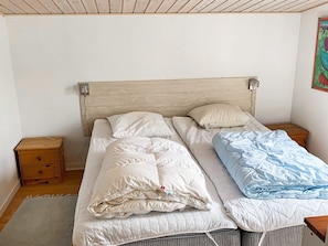 A single bed with a wooden headboard, two bedside tables, and a wall-mounted light fixture.