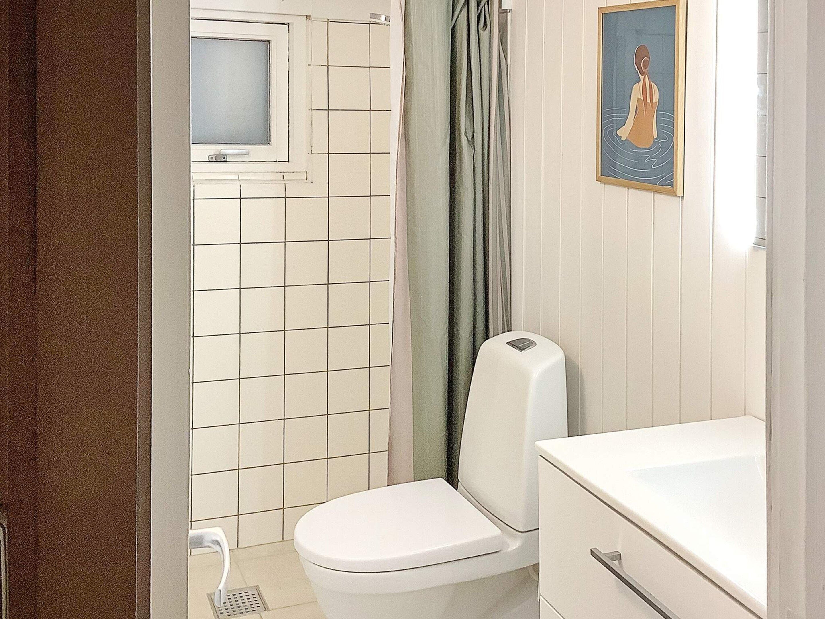 A bathroom with a toilet, a shower area, and a sink.
