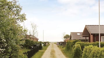 A rural road leading to houses with a clear sky.