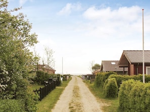 A rural road leading to houses with a clear sky.