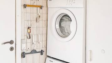 Una lavadora de carga frontal con la etiqueta de la marca Samsung, una puerta de madera con perchero y un picaporte.