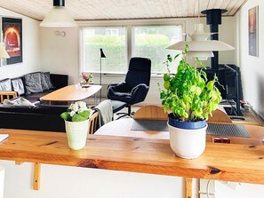A living room with a sofa, a chair, a table, and two potted plants.