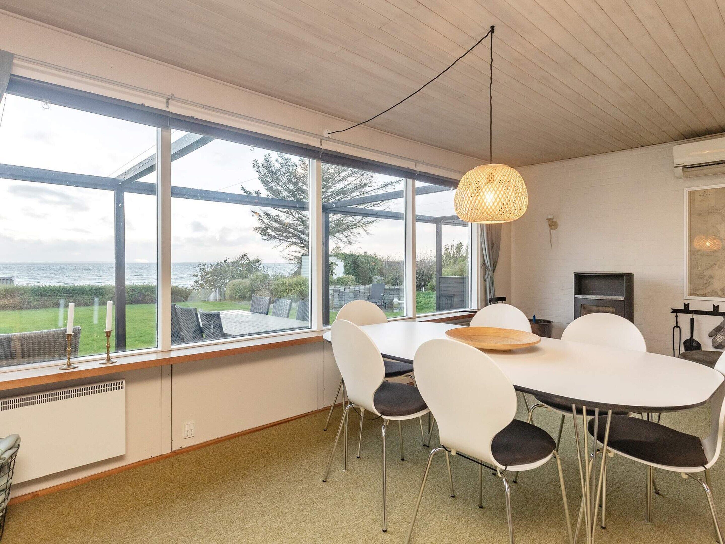 A dining area with a table and chairs, large windows, and a hanging light fixture.