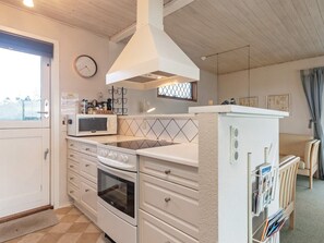 A kitchen with white cabinets, a microwave, an oven, a sink, and a window with a view.