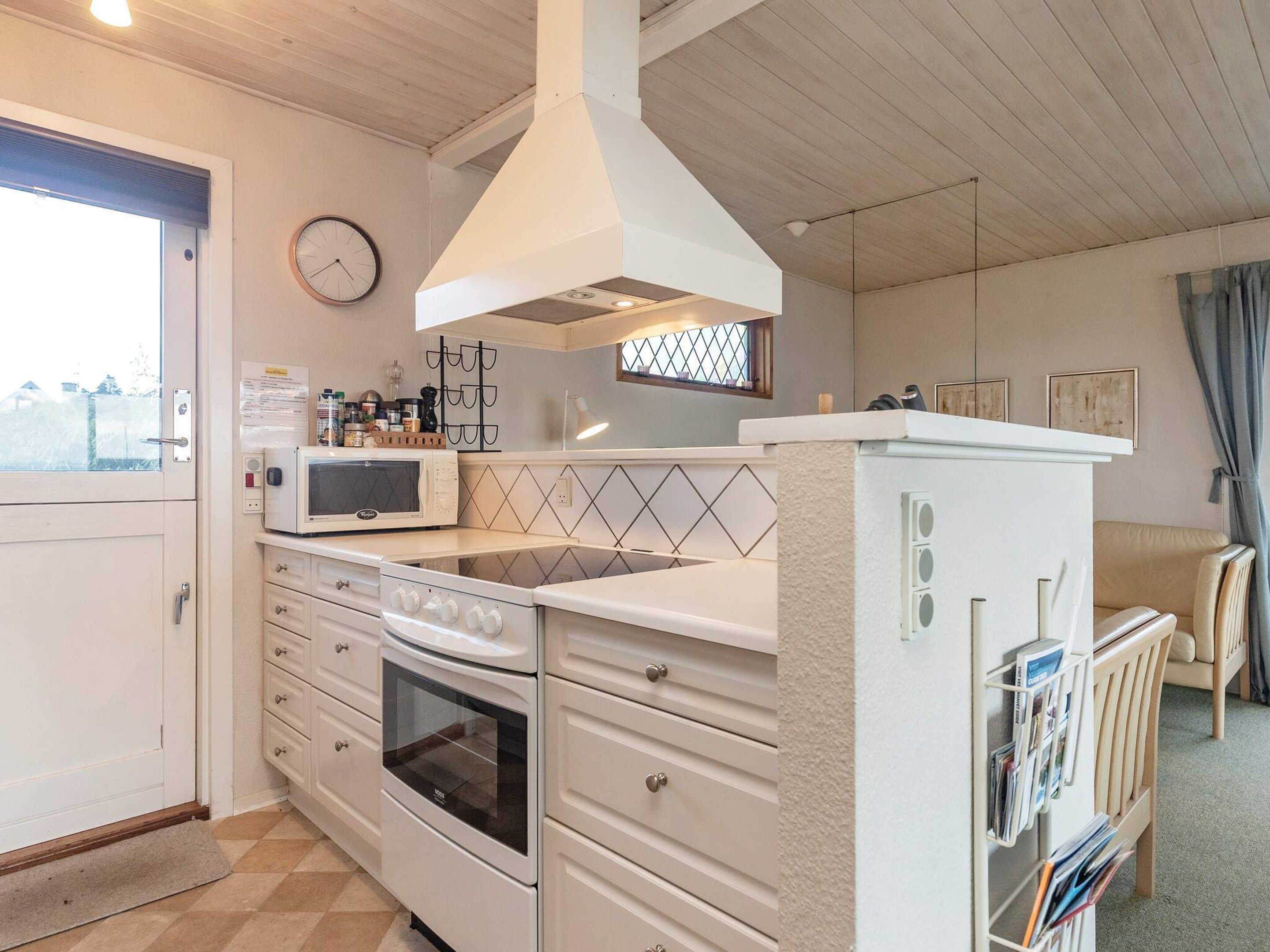 A kitchen with white cabinets, a microwave, an oven, a sink, and a window with a view.
