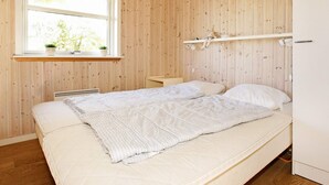Une pièce avec un lit, une fenêtre donnant sur un beau paysage, une étagère avec une plante et une lampe fixée au mur.