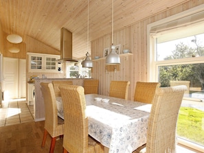 A dining area with wicker chairs and a table, wooden ceiling, and a view through a window. - 5 Star Holiday Home in Vestervig (Vestervig)