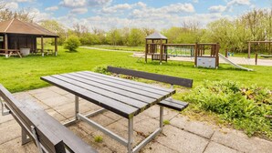 Un parque con una mesa de picnic, un pabellón y juegos infantiles.