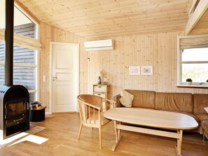 Um quarto aconchegante com decoração em madeira, um sofá, uma mesa, uma cadeira e uma lareira a lenha.
