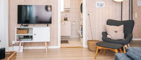 A modern living room with a flat-screen TV, a grey armchair, and a white cabinet.