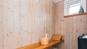 Una sala de sauna con paredes de madera, un banco, una mesa de madera y una ventana.
