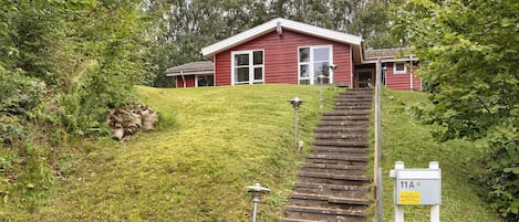 A red house with a front porch and a set of stone steps leading to the entrance.