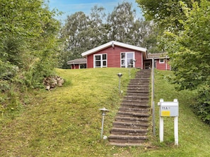 Ett rött hus med en veranda och en trappa av sten som leder upp till entrén.