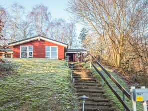 A red building with a staircase leading up to a porch.