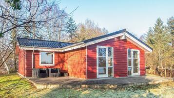A red wooden house with a porch, large windows, and a sloped roof.