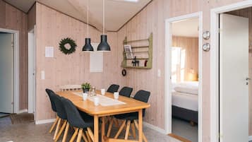 Un interior moderno con una mesa de comedor de madera, sillas, lámparas colgantes y un tragaluz visible.