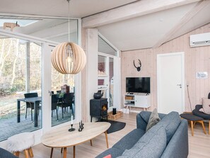 A modern living room with a large TV, a fireplace, and a dining area with outdoor seating. - 8 Person Holiday Home in Borkop (Borkop)