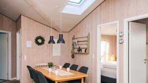 A modern, well-lit dining area with a wooden table and chairs, a small plant, and a wall-mounted shelf with decorative items. - 8 Person Holiday Home in Borkop (Borkop)