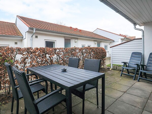 An outdoor patio with a table and chairs, a hedge, and a house in the background. - 4 Person Holiday Home in Aeroskobing (Aeroskobing)