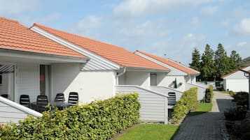 A row of white buildings with red-tiled roofs and a paved pathway.