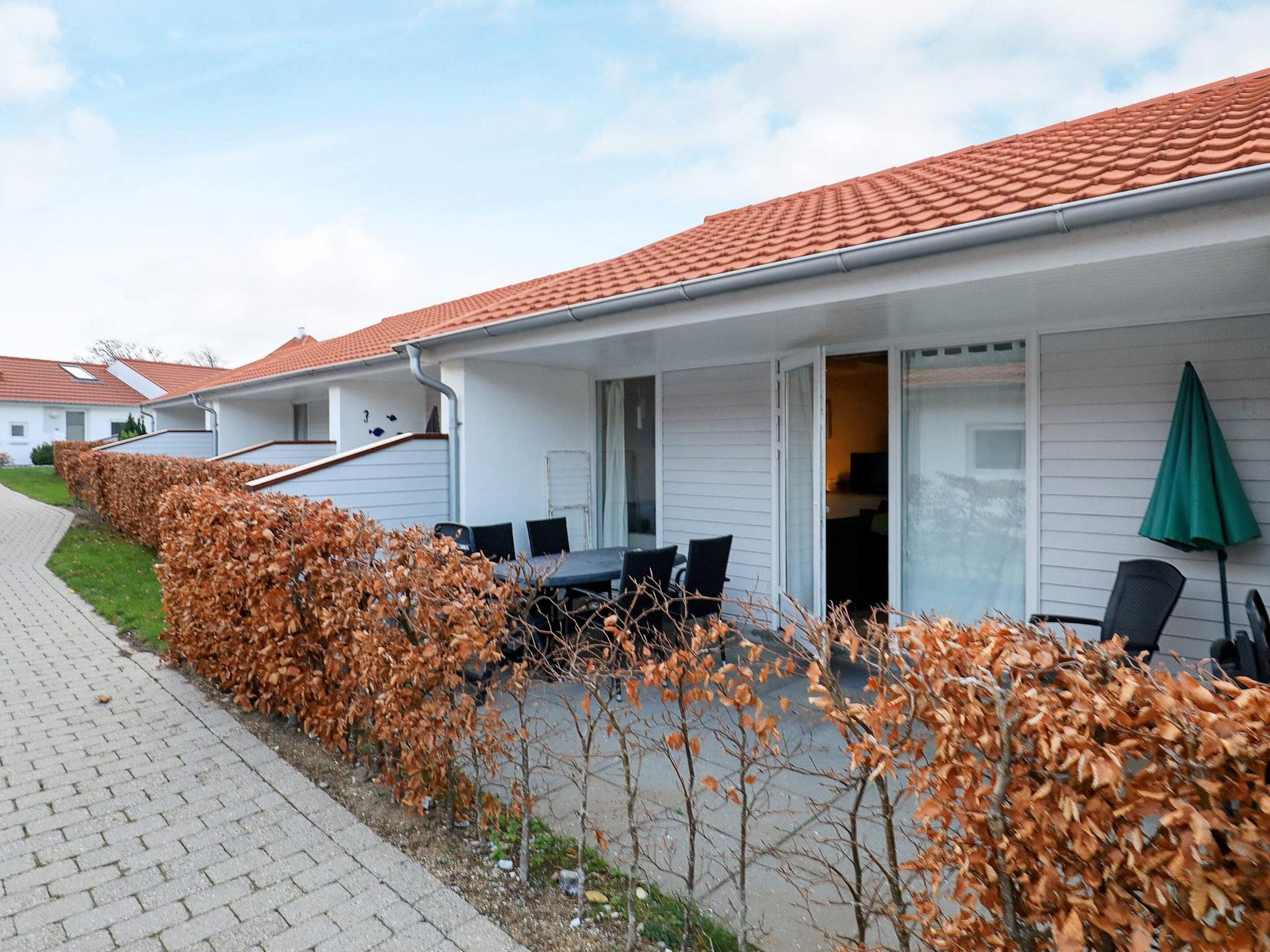 A row of single-story buildings with a uniform exterior design, featuring a tiled roof and a paved walkway.