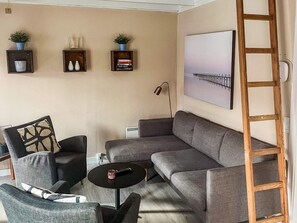 A living room with a grey sofa, two armchairs, a coffee table, and a ladder against the wall. There are three shelves with decorative items and a painting above the sofa. - 4 Person Holiday Home in Aeroskobing (Aeroskobing)