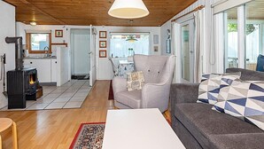 A cozy living room with a fireplace, a sofa, a chair, and a dining area with a table and chairs.