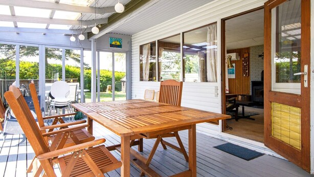 A wooden deck with a table and chairs, a covered area with a ceiling, and a door leading to an interior space with a fireplace. - 5 Person Holiday Home in Odder-by Traum (Odder)