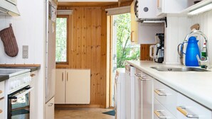 A compact kitchen with wooden walls, a built-in oven, and a sink with a blue kettle. - 5 Person Holiday Home in Odder-by Traum (Odder)