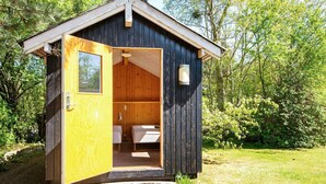 A small wooden cabin with an open door revealing a single bed and a small window. - 5 Person Holiday Home in Odder-by Traum (Odder)