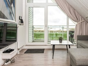 A modern living room with a television, a small table with a plant, and a grey sofa. - Holiday Home in Wendtorf (Wendtorf)