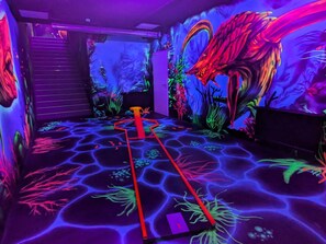An indoor space with a glowing path, vibrant murals, and a staircase.
