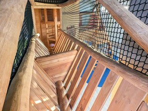 A wooden staircase with a metal railing and a mesh barrier. - Holiday Home in Wendtorf (Wendtorf)