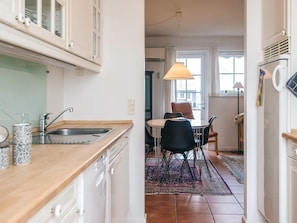 A compact kitchen with a sink, a dining area with a table and chairs, and a refrigerator.