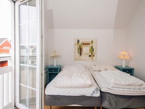 A bedroom with two beds, a window, and a painting on the wall. - 4 Star Holiday Home in Blavand (Blavand)