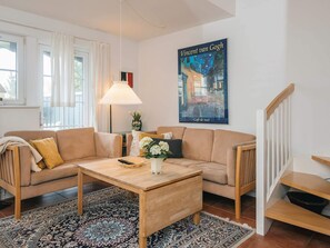 A living room with a sofa, a coffee table, a lamp, a poster, and a staircase.