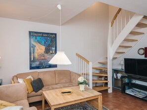 A living room with a sofa, coffee table, and a poster of Vincent van Gogh's 'Café de nuit'. - 4 Star Holiday Home in Blavand (Blavand)