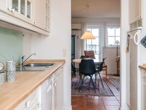 A kitchen with a sink, cabinets, and a dining area with chairs and a table. - 4 Star Holiday Home in Blavand (Blavand)
