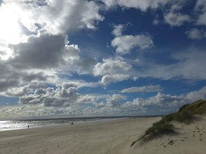 A beach with a clear sky and clouds, sandy terrain, and dunes. - 4 Star Holiday Home in Blavand (Blavand)