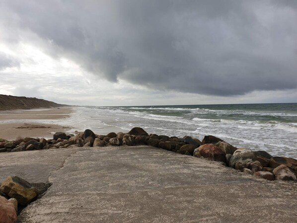 A beach with a rocky shoreline and waves crashing onto the sand.