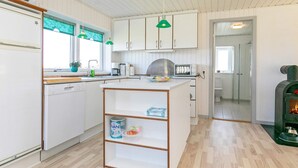 A modern kitchen with white cabinets, a central island, and a built-in stove.