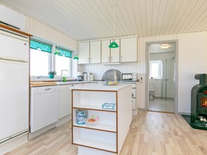 A modern kitchen with white cabinets, a central island, and a built-in stove.