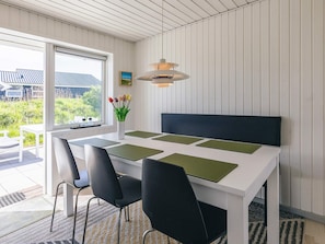 Ein moderner Essbereich mit einem weißen Tisch, schwarzen Stühlen und einer Pendelleuchte.