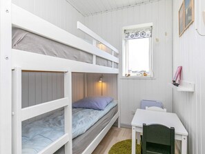 A bunk bed room with a desk and a window.