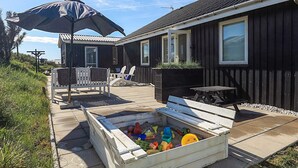 A house with a patio, outdoor seating, and a sandbox with toys.