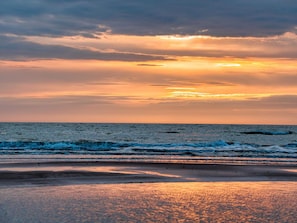 En strand med bølger og en solnedgang.