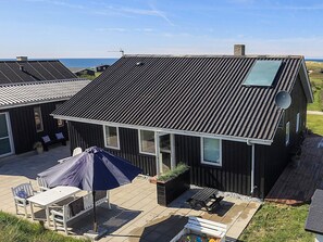 A residential building with a sloped roof, satellite dish, and a patio area with outdoor furniture.