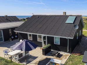 A house with a sloped roof, satellite dish, and a patio with outdoor furniture. - 4 Star Holiday Home in Lokken (Lokken)